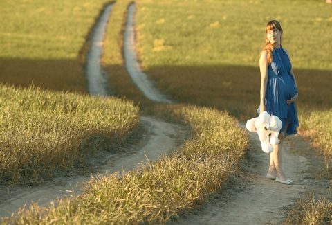 girl walking along the road in a field alone